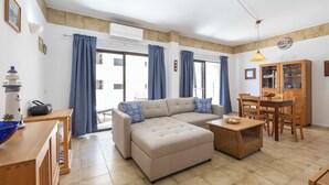 Ein Wohnzimmer mit einer Couch, einem Esstisch und einer Lampe.