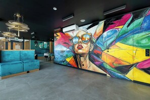 Un interior moderno con un sofá azul, un mural abstracto colorido e iluminación colgante.