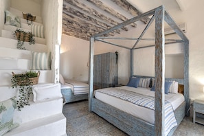 Una camera da letto con un letto a baldacchino, una scala con cuscini e un soffitto in legno.