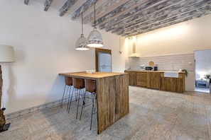 Una cucina con isola in legno, sgabelli da bar, luci a sospensione e un frigorifero.