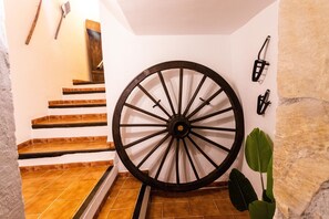 Una escalera con una rueda de madera grande, una planta y luces fijadas a la pared.