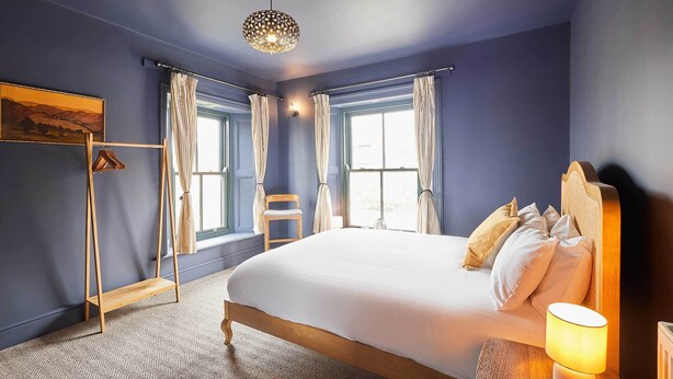 Ein Schlafzimmer mit einem großen Bett, einem Hängekorbsessel, einer Stehlampe und einem Bild an der Wand.