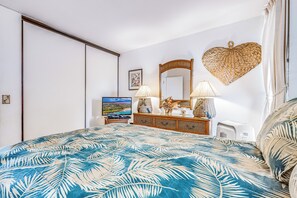 Ein Schlafzimmer mit Bett, Kommode, Spiegel, Fernseher und Wanddekoration in Herzform.
