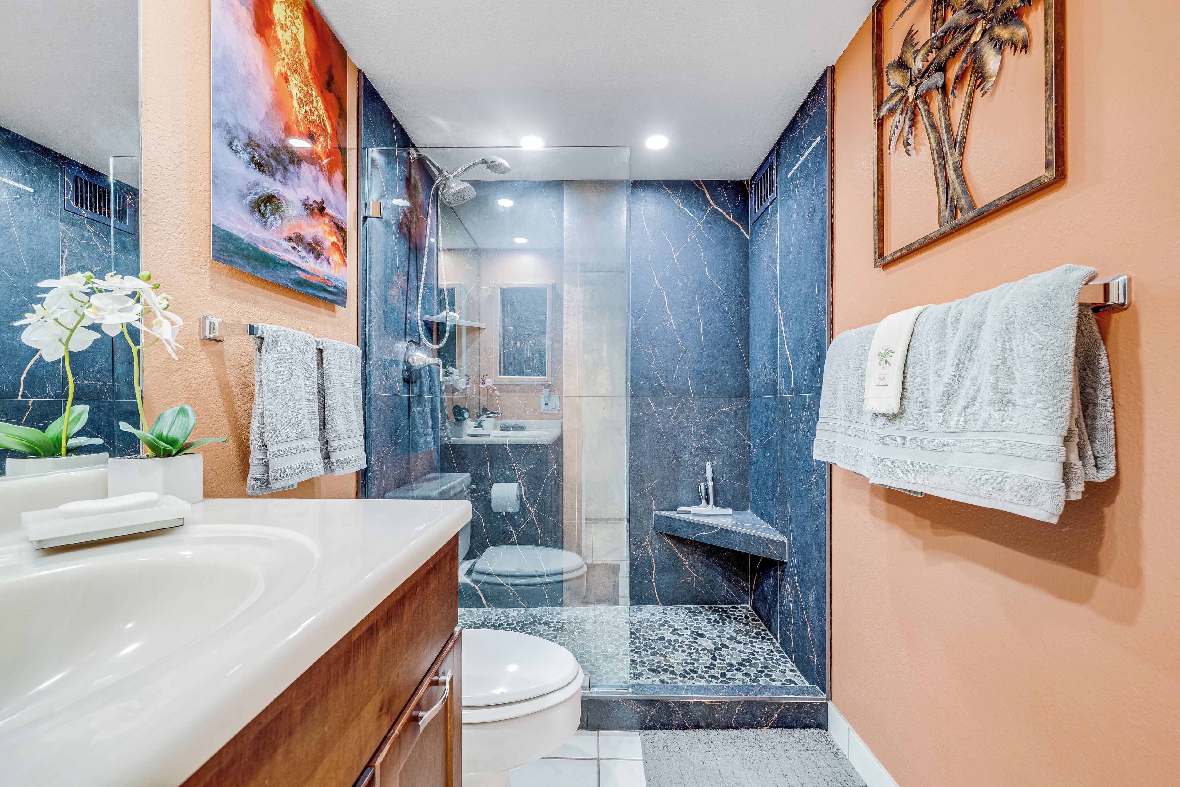 Une salle de bain moderne avec une douche à parois de verre, un lavabo en marbre et des toilettes.