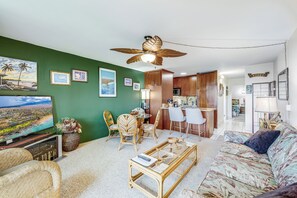 A living room with a television, wicker furniture, a ceiling fan, and framed pictures on the wall. - Maui Vista #2-218 Close to Beach, Pickleball Courts, Full A/C (Kihei)