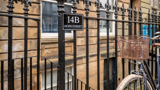 Una valla metálica con un cartel que dice '14B HOPE STREET'.