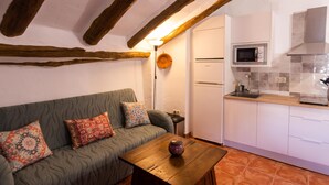 Una sala acogedora con un sofá, una mesa de madera y una cocina con microondas.