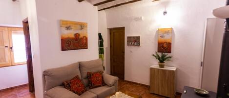 A living room with a sofa, a coffee table, a small cabinet, and a door.