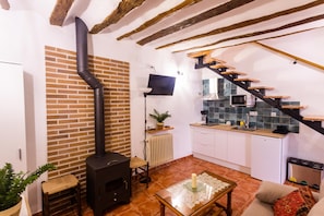 A compact living space with a kitchen, a fireplace, and a staircase.