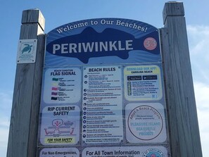 Ein Schild mit Strandregeln, Sicherheitsinformationen und einer Willkommensbotschaft für Periwinkle Beach.
