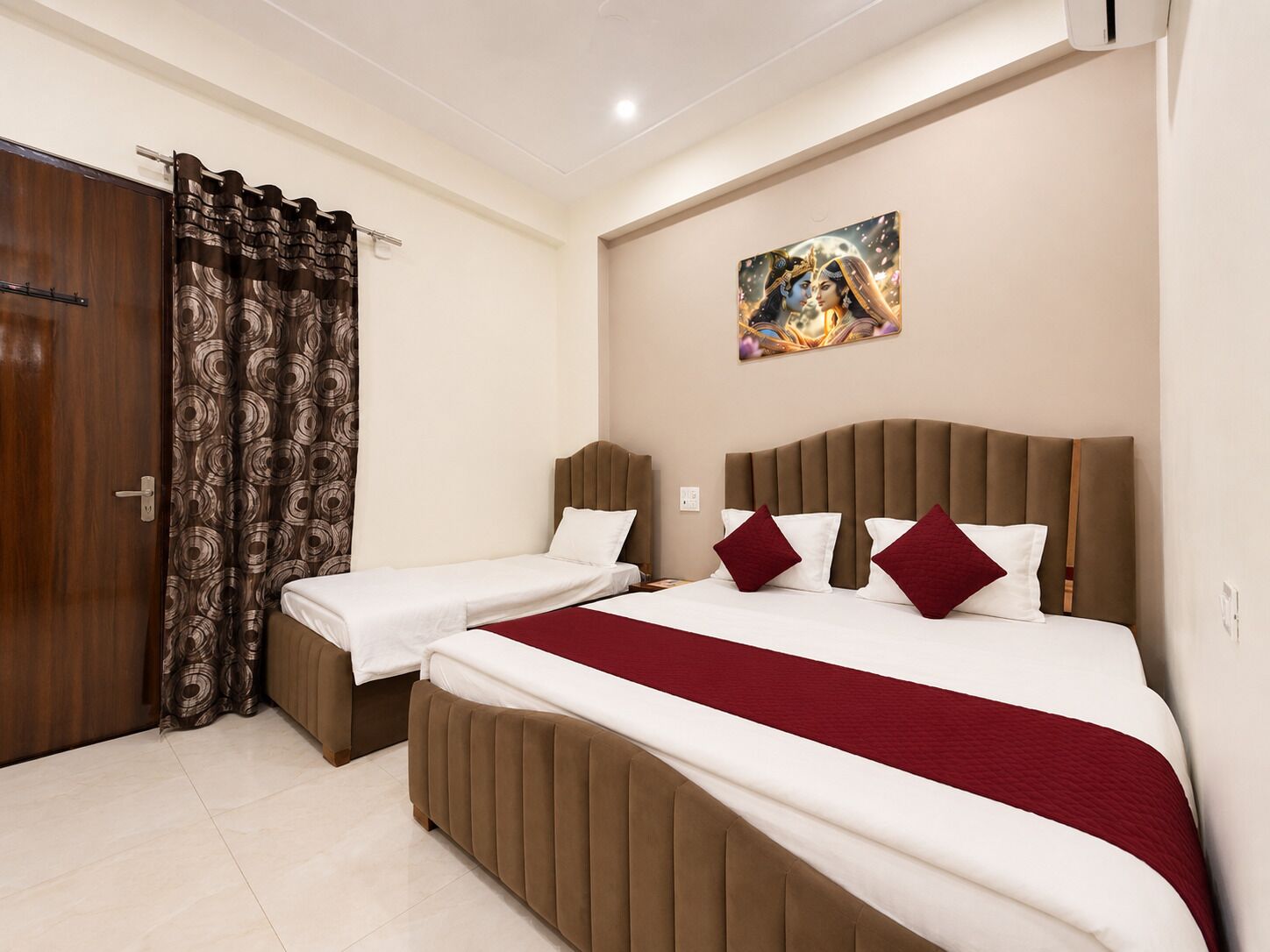 A hotel room with two beds, a wooden door, patterned curtains, and a painting on the wall.