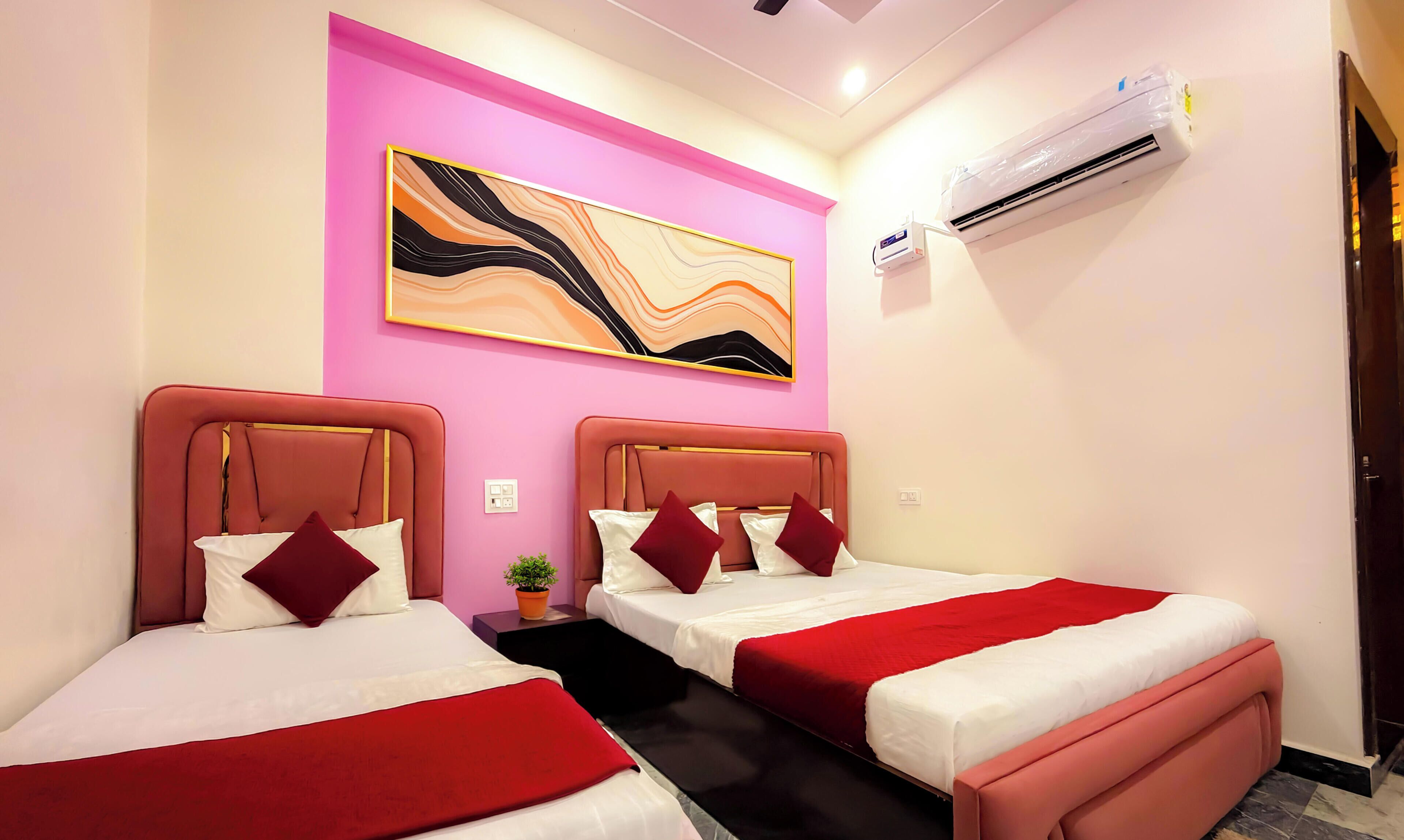 A hotel room with two beds, a pink accent wall, a modern abstract painting, an air conditioning unit, and a small potted plant.
