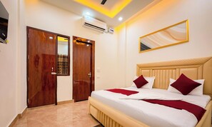 Habitación de hotel con cama, armario, equipo de aire acondicionado y un espejo en la pared.
