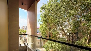 Un balcón con vista a un árbol y edificios.