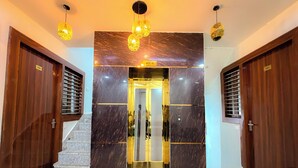 Entrada de hotel con pared de mármol, puertas de madera y una escalera que conduce a un ascensor.