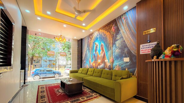 Vestíbulo de hotel con sofá verde, una araña de cristal, un mural y un cartel de 'No Fumar'.