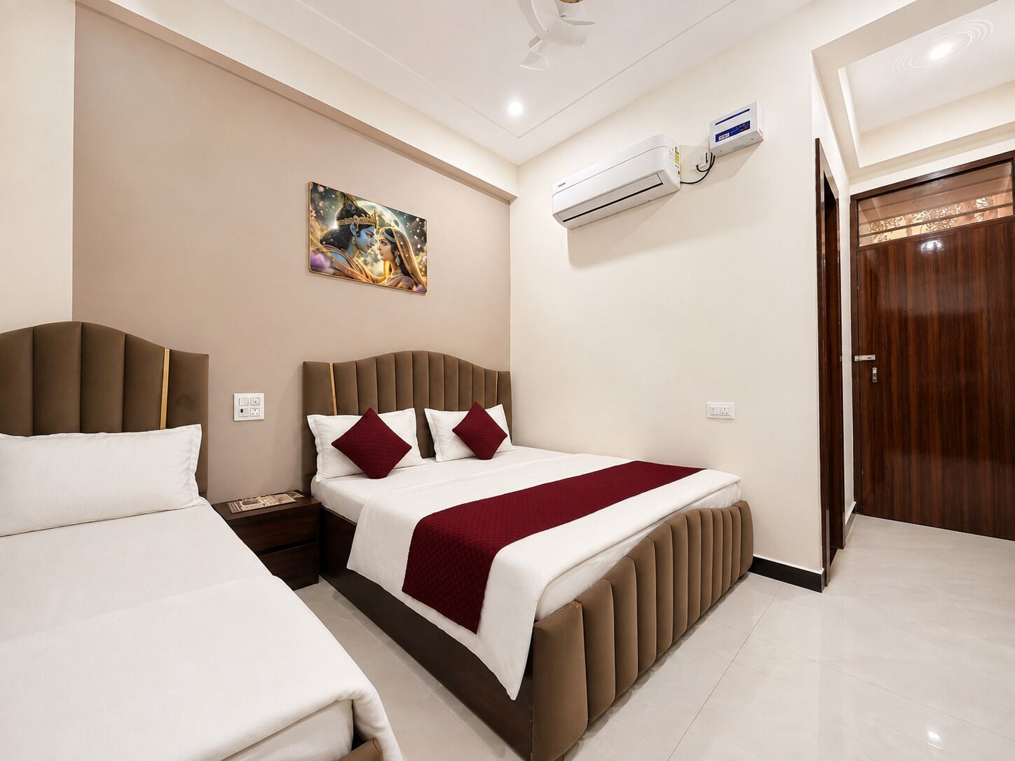 A hotel room with two beds, a painting on the wall, an air conditioning unit, and a wooden door.