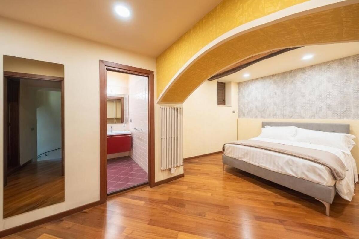 Ein Schlafzimmer mit einem Bett, einer Tür zu einem Badezimmer und einem Heizkörper.