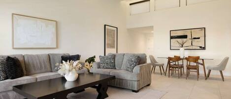 A modern living room with a sofa, coffee table, and dining area.