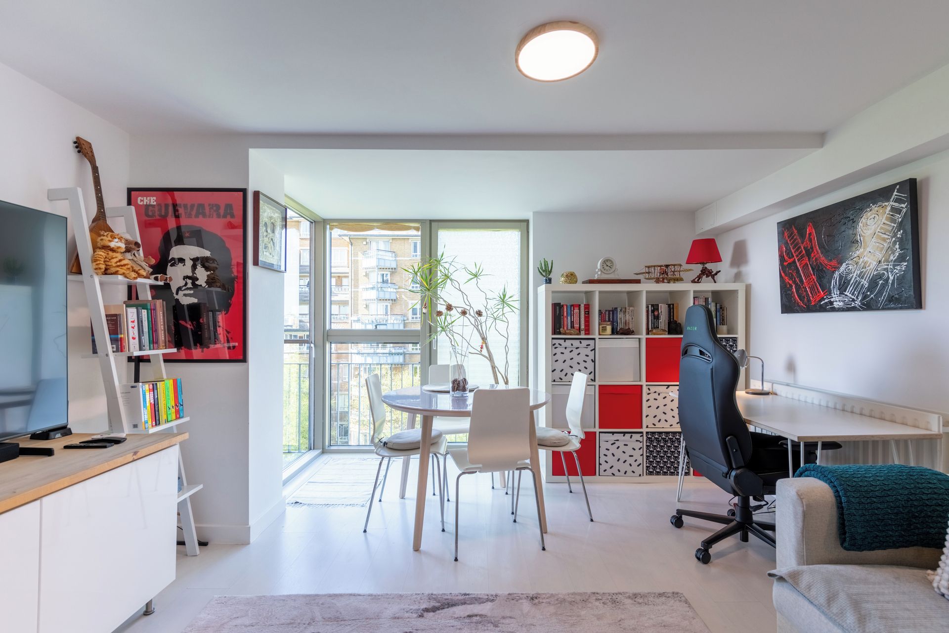 Ein stilvolles Wohnzimmer mit Essbereich, einem Gaming-Sessel und einer Bücherwand.