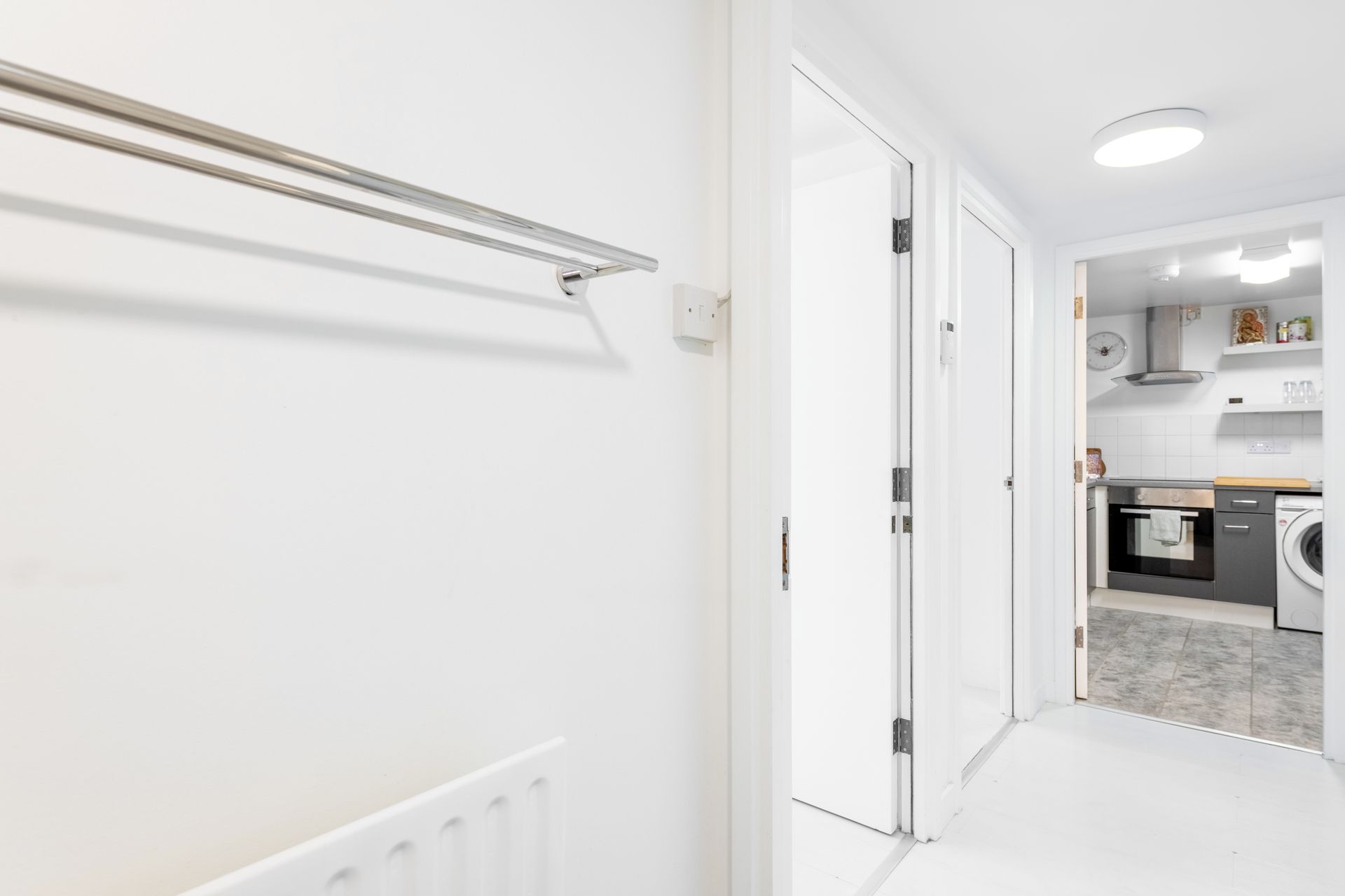 Un couloir mène à une cuisine équipée d’un lave-linge et d’une cuisinière.