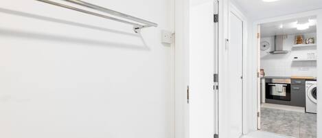 Un couloir mène à une cuisine équipée d’un lave-linge et d’une cuisinière.