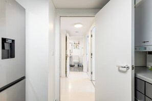 Ein schmaler Flur, der zu einem Badezimmer mit Toilette, Waschbecken und einem kleinen Tisch führt.