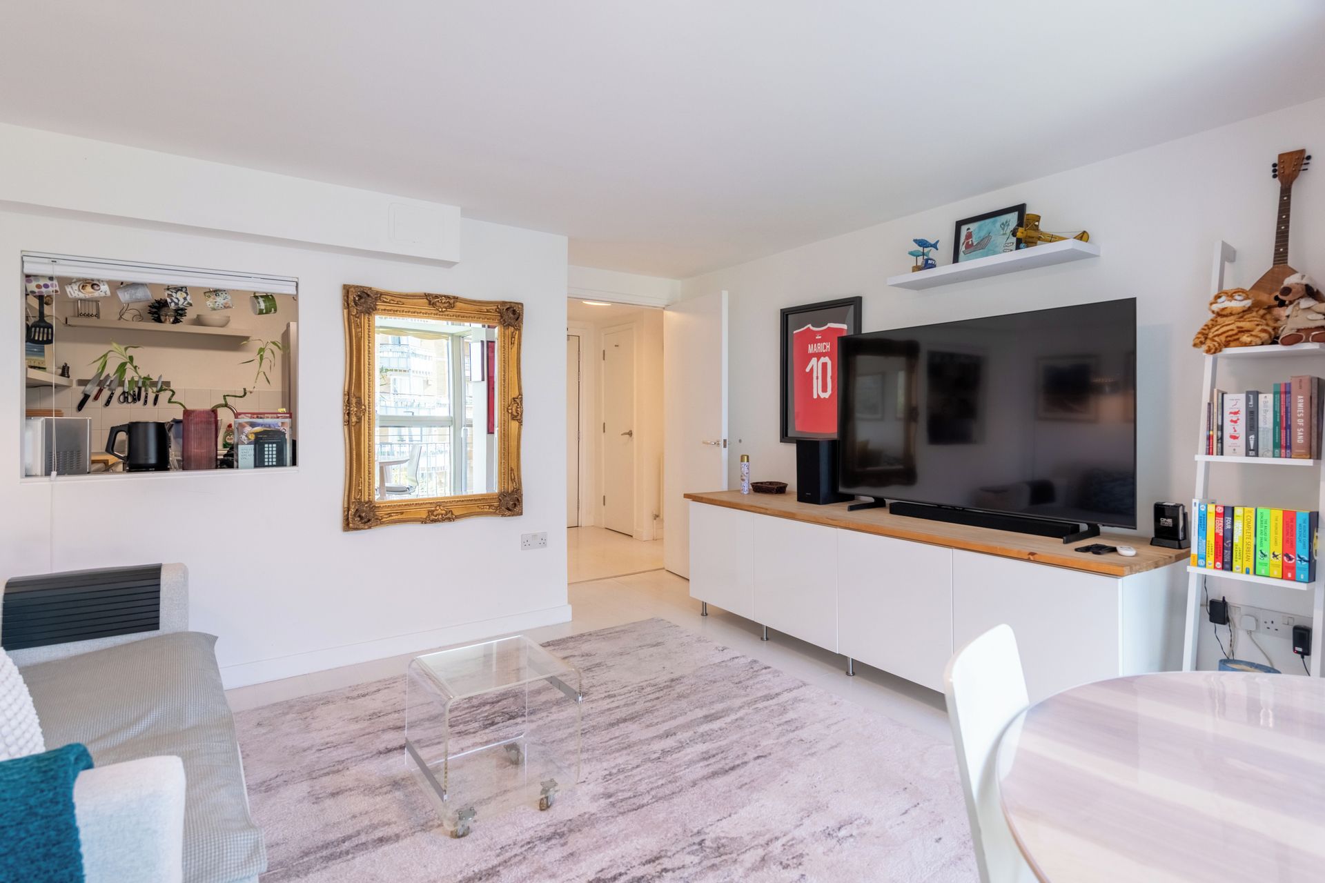 Una sala de estar moderna con un televisor de pantalla plana, una mesa de centro y una estantería.