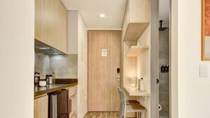 Eine kompakte Küche mit Holzausstattung, einem Edelstahlkühlschrank und einer kleinen Essecke mit einem Stuhl.