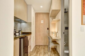 Eine kompakte Küche mit Holzausstattung, einem Edelstahlkühlschrank und einer kleinen Essecke mit einem Stuhl.