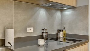 Eine moderne Küche mit einer Edelstahl-Arbeitsfläche, einem Papiertuchhalter, einer Kaffeemaschine und einer Flasche Öl.