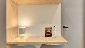 Ein Holztisch mit einer weißen Lampe, einer Doona-Flasche und einem gerahmten Bild.