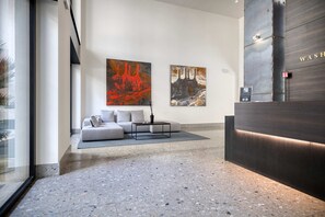 A modern lobby with a sofa, two abstract paintings, a reception desk, and a terrazzo floor. - w Bright 1BR Near to the Center of Milan (Milan)