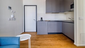 Een moderne keuken met grijze kastjes, een wit aanrecht en een houten vloer.