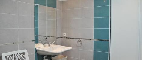 A bathroom with a white sink, a mirror, and a white chair.