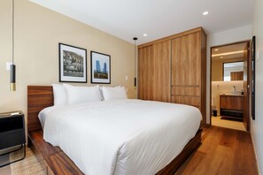 A hotel room with a large bed, wooden wardrobe, and a bathroom visible through an open door. - w Deluxe 2BR w Private Terrace in Hipodromo (Mexico City)
