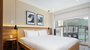 A modern hotel room with a large bed, two framed pictures on the wall, a small side table, and a large window with a view of buildings. - w Deluxe 2BR w Private Terrace in Hipodromo (Mexico City)