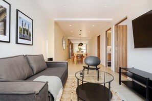 A modern living room with a sofa, a glass coffee table, and a flat-screen TV. - w Deluxe 2BR w Private Terrace in Hipodromo (Mexico City)