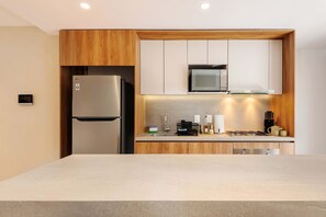 A modern kitchen with a built-in microwave, stainless steel refrigerator, and wooden cabinetry. - w Deluxe 2BR w Private Terrace in Hipodromo (Mexico City)