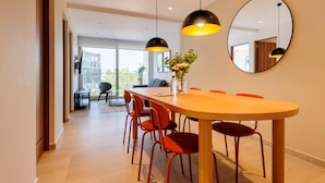 A modern dining area with a long table, red chairs, pendant lights, a vase with flowers, and a large mirror on the wall. - w Deluxe 2BR w Private Terrace in Hipodromo (Mexico City)