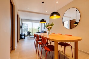 A modern dining area with a long table, red chairs, pendant lights, a vase with flowers, and a large mirror on the wall. - w Deluxe 2BR w Private Terrace in Hipodromo (Mexico City)