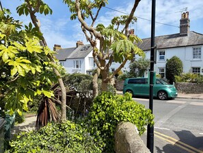 A residential street with a green car parked on the side, houses with white exteriors, and a tree in the foreground. - Downs Gate Cottage, Meads Village - Coast & South Downs On Your Doorstep (Eastbourne)