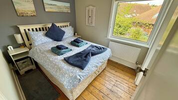 Una camera da letto con un letto, comodini, una finestra e opere d'arte alle pareti.