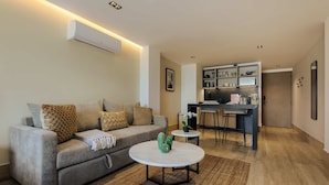 Ein modernes Wohnzimmer mit einer Couch, einem Couchtisch und einer Küchenzeile im Hintergrund.