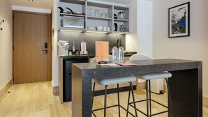 A modern kitchen with a granite countertop, bar stools, and a built-in shelving unit with kitchenware. - w Stylish Loft w/ Balcony in Parque Mexico (Mexico City)
