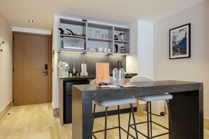 A modern kitchen with a granite countertop, bar stools, and a built-in shelving unit with kitchenware. - w Stylish Loft w/ Balcony in Parque Mexico (Mexico City)