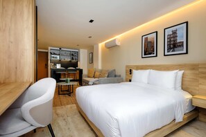 A modern hotel room with a large bed, a desk, a chair, a sofa, and a kitchenette in the background. - w Stylish Loft w/ Balcony in Parque Mexico (Mexico City)