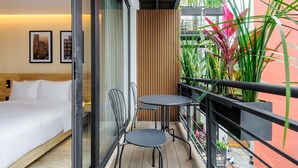 A balcony with a bed, two chairs, a small table, and potted plants. - w Stylish Loft w/ Balcony in Parque Mexico (Mexico City)