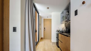 A narrow hallway with a sliding door, a wooden door at the end, and a kitchen area with cabinets and appliances. - w Airy Loft W/balcony in Parque Mexico (Mexico City)