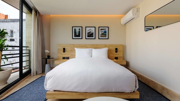 A modern bedroom with a wooden headboard, white bedding, a large window with curtains, and a potted plant. - w Airy Loft W/balcony in Parque Mexico (Mexico City)